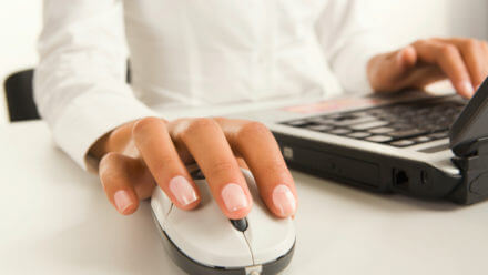 Womans hands touching computer mouse and keys of black opened laptop
