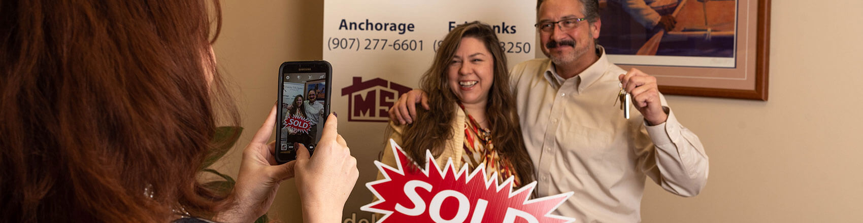 Title agent taking a picture of happy new homeowners in the office.