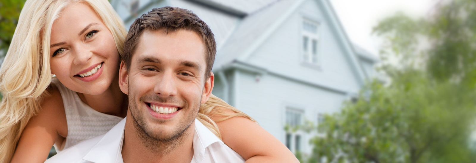 Happy young couple in front of first home purchase.